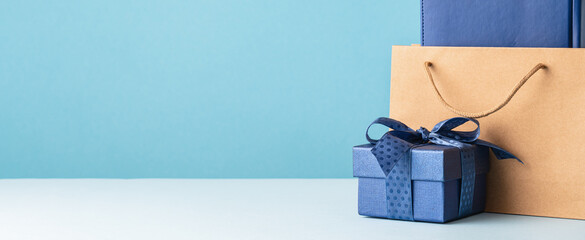Small luxury gift box with blue bow paper bag and agenda. Side view. Fathers day or Valentines day gift for him. Corporate gift concept or birthday party. Festive sale copy space banner