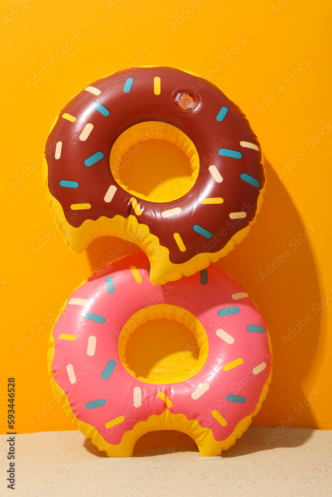 Rubber rings on sand against orange background Rubber rings on sand against orange background