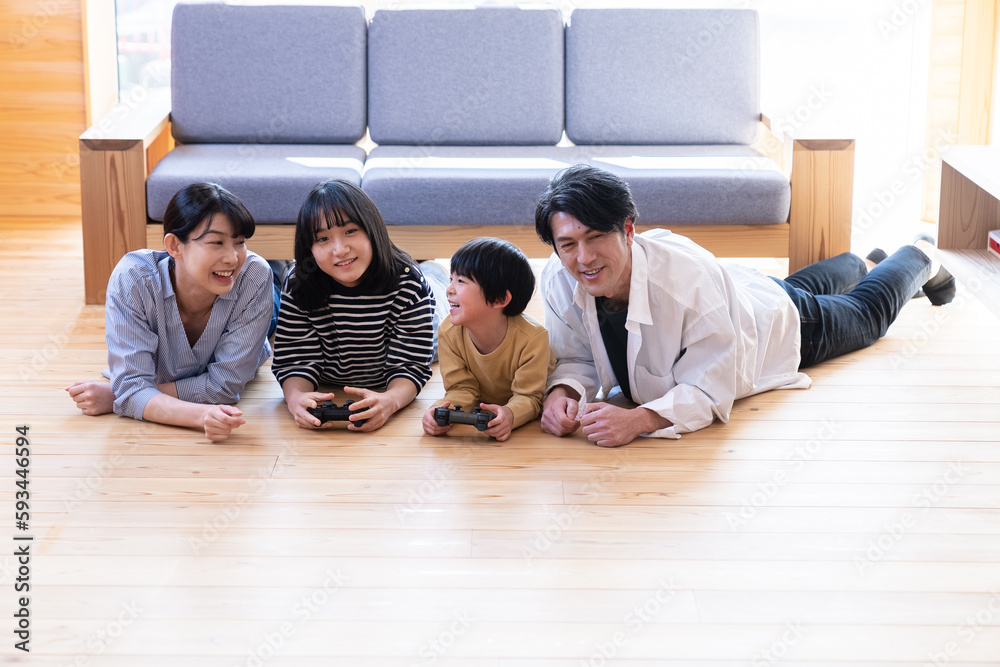 Fototapeta premium 床にうつ伏せになってゲームをする家族