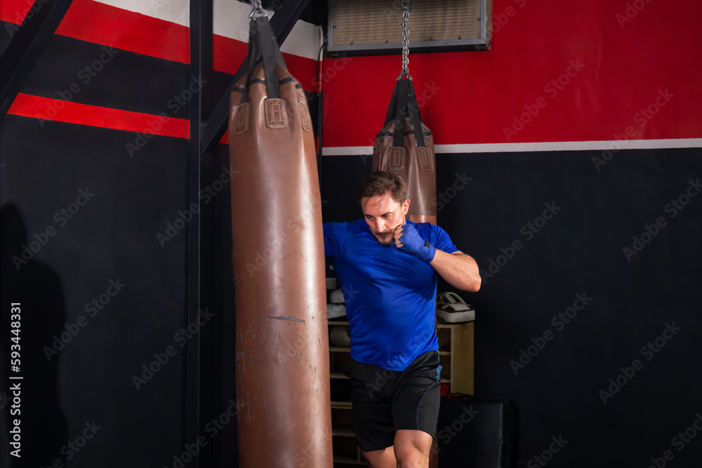 Man boxer exercising punches with boxing bag in gym, Boxer hitting a huge punching bag at a boxing studio