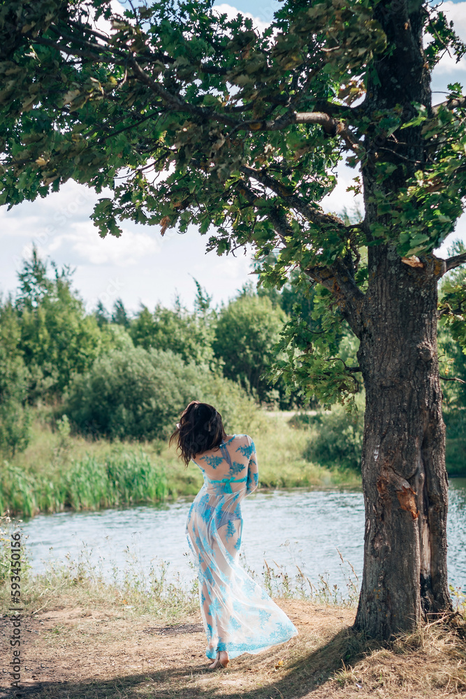 young girl with a sexy ass in a swimsuit and tunic poses on beach by river in summer young girl with a sexy ass in a swimsuit and tunic poses on beach by river in summer