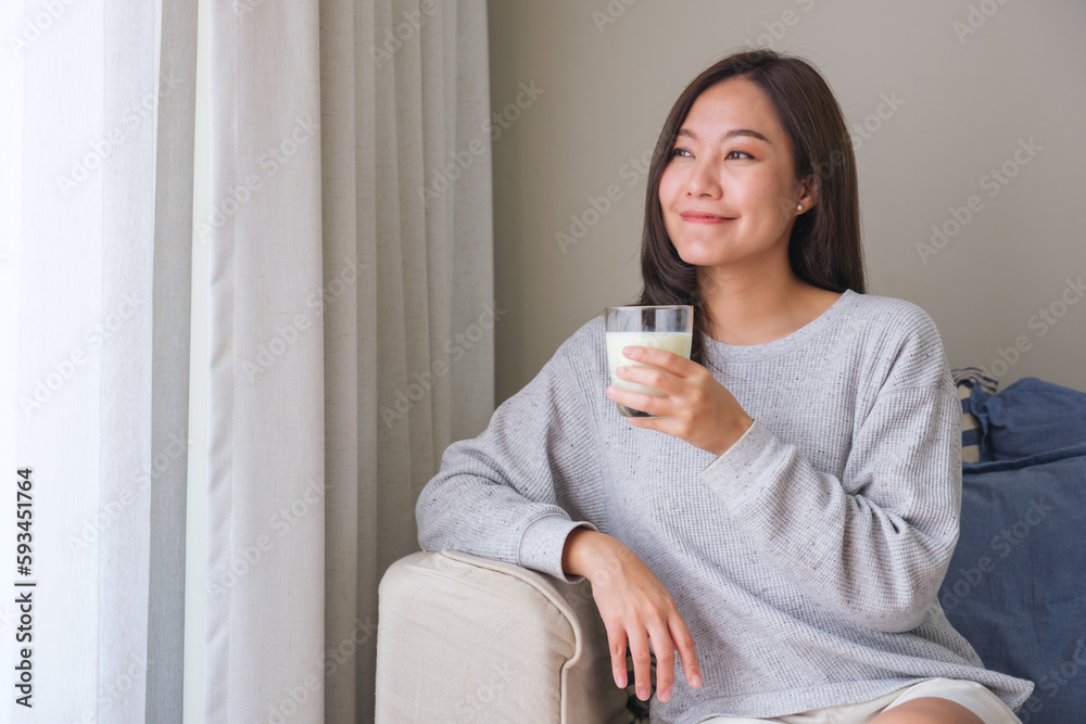 Portrait image of a young woman holding and showing a glass of fresh milk Portrait image of a young woman holding and showing a glass of fresh milk