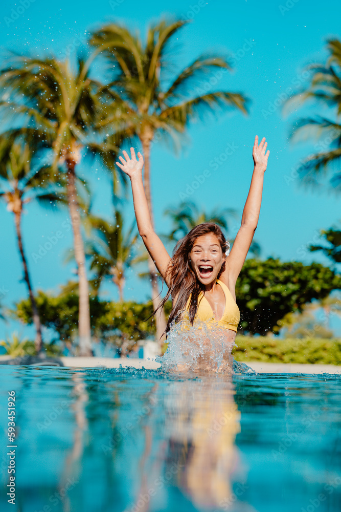 Travel resort concept. Happy fun woman jumping in pool screaming of joy at luxury hotel vacation. Multiethnic girl