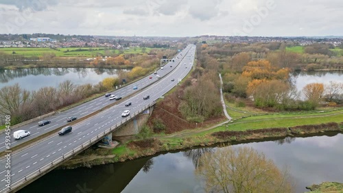 Aerial drone cinematic video footage of the M1 Motorway near the city of Wakefield, West Yorkshire, UK. Showing the busy motorway full of traffic and commercial buildings. photo