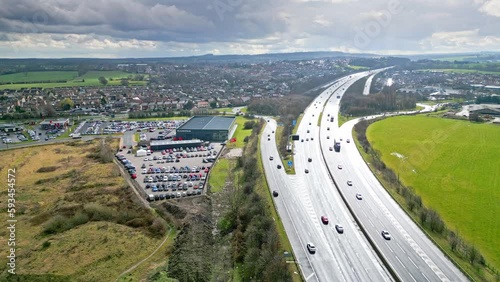 Aerial drone cinematic video footage of the M1 Motorway near the city of Wakefield, West Yorkshire, UK. Showing the busy motorway full of traffic and commercial buildings. photo
