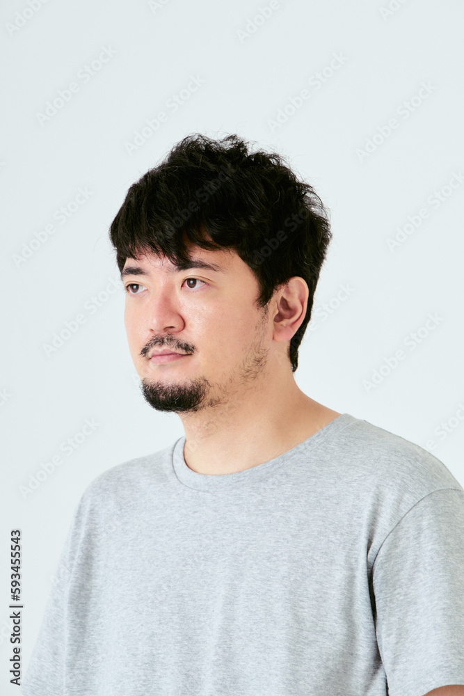 Fototapeta premium 白背景で右側を向いた30代の1人の髭を生やした日本人男性の人物の上半身