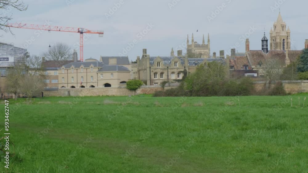 Grassy field fronts construction cranes and classic English architecture, England Grassy field fronts construction cranes and classic English architecture, England