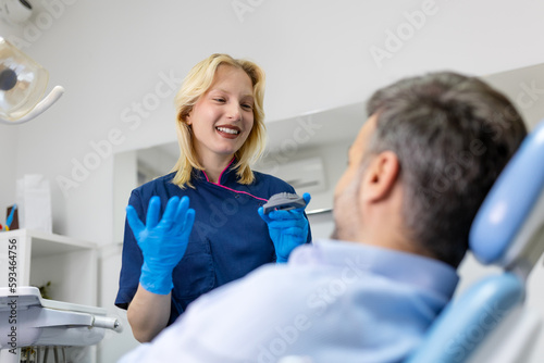Dentist showing dental plaster mold to the patient. Dentist doctor showing jaw model at dental clinic, dental care concept. Dental care concept.