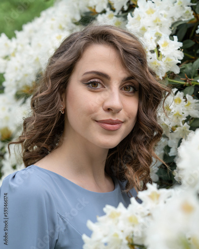 Beautiful young girl among white flowers of rhododendrons. photo