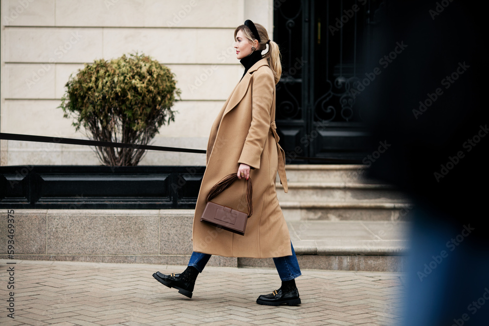 Φωτογραφία Side view beautiful woman walking street in fashionable spring or autumn clothes cashmere coat, jeans, loafers shoes and small bag