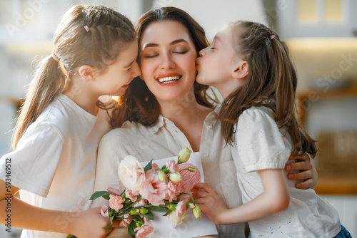 Daughters giving mother bouquet of flowers.
