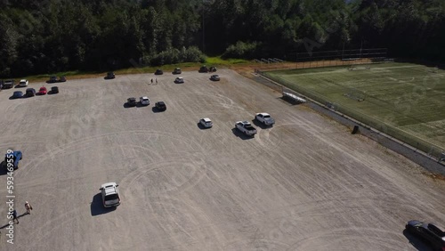 A white pick up truck driving in circles, kicking up dust and making donuts at a fair or festival event in Squamish BC from an aerial view of the parking lot with a 4K drone. photo