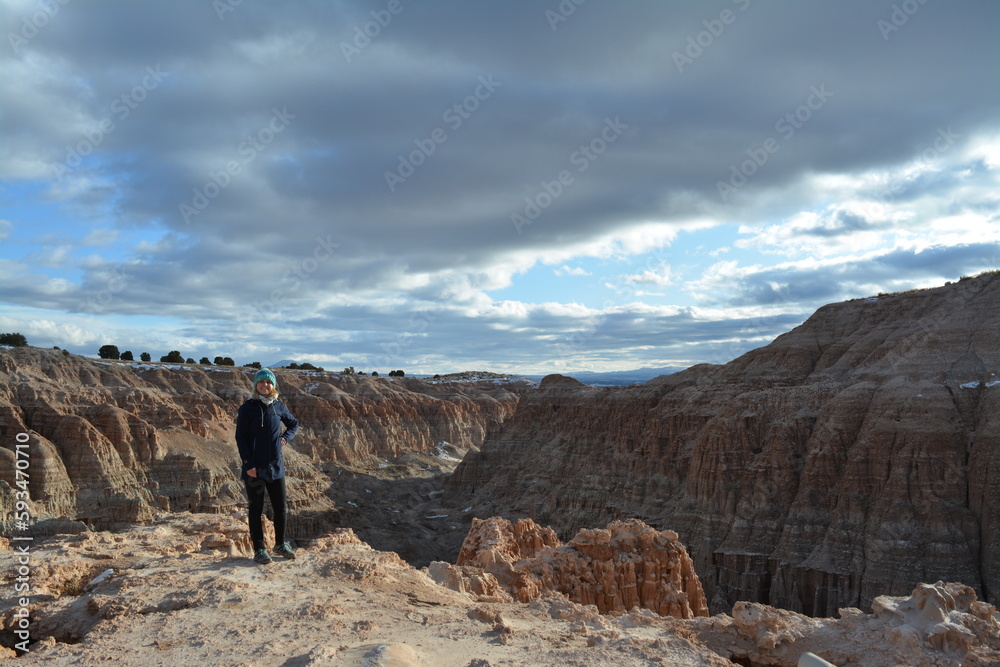 woman in the Cathedral Gorge State Park on a cold day in December, located in a long, narrow valley in southeastern Nevada, where erosion has carved patterns in bentonite clay