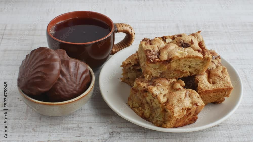 Festive tea party with homemade fruit pie and marshmallows in chocolate icing. Close-up of a cup of black tea, plates with pieces of apple pie and cup with sweet chocolate marshmallows. Sweet dessert