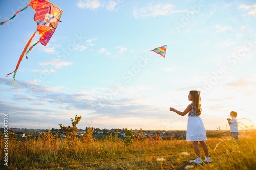 Children launch a kite in the field at sunset