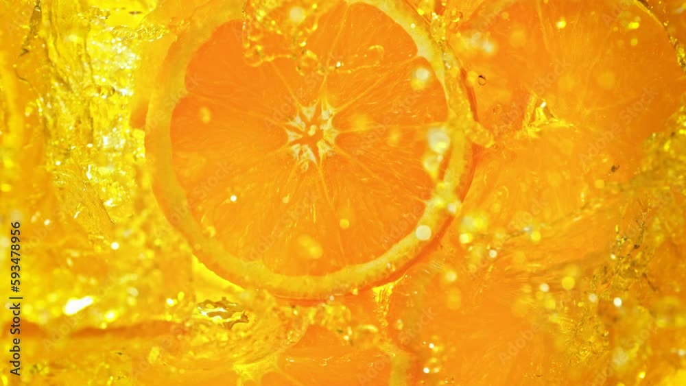Super Slow Motion Shot of Fresh Orange Slices Falling into Lemonade Whirl at 1000 fps.