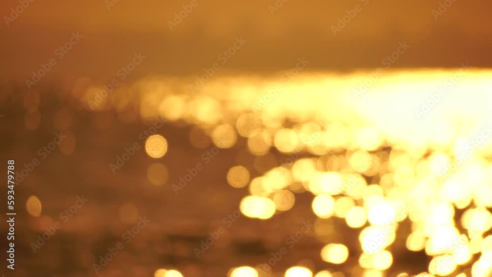 Blurred golden sea at sunset. The sun reflects and sparkles on the waves with bokeh, illuminating the golden sea. Holiday recreation concept. Abstract nautical summer ocean sunset nature background. Blurred golden sea at sunset. The sun reflects and sparkles on the waves with bokeh, illuminating the golden sea. Holiday recreation concept. Abstract nautical summer ocean sunset nature background.