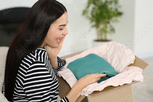 Happy young woman with parcel at home. Internet shopping