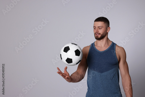 Athletic young man with soccer ball on light grey background. Space for text