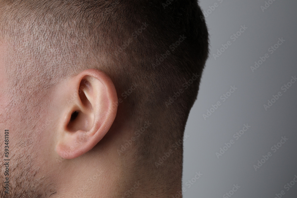 Man on grey background, closeup of ear Man on grey background, closeup of ear