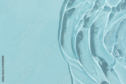 Transparent serum gel with hyaluronic acid for the face on a blue background. The texture of a cosmetic product with oxygen bubbles. Wellness and beauty concept.