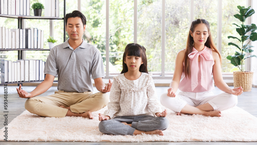 Young asian family with daughter sit on floor practice yoga together, happy parents with girl child rest on floor meditate relieve negative emotions on weekend at home. 16:9 ratio Young asian family with daughter sit on floor practice yoga together, happy parents with girl child rest on floor meditate relieve negative emotions on weekend at home. 16:9 ratio
