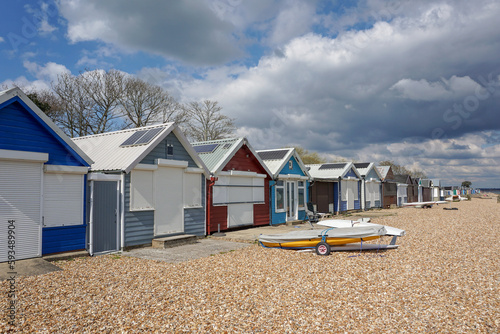 A line of colorful beach huts on stony beach. sunny day on the coast during spring day. seaside beach cabins © Paul Cartwright
