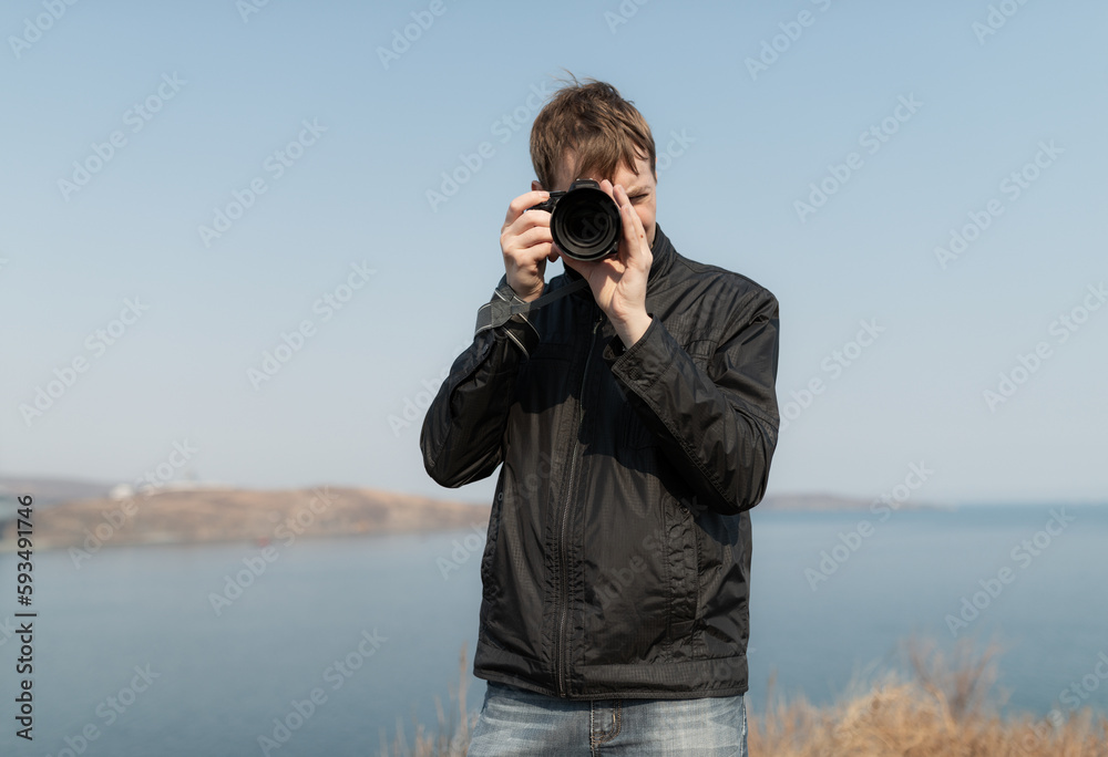 Young man with a camera. Outdoors. Selective focus.