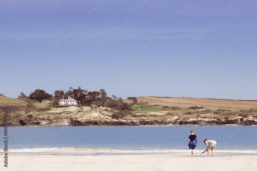 Two young children beach combing along the shoreline near Padstow, Cornwall Two young children beach combing along the shoreline near Padstow, Cornwall