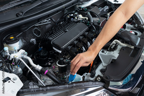 Asian girl's hand checking level of coolant car engine. © Paveena