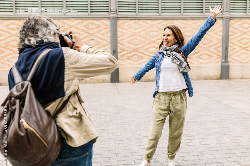 © Xavier Lorenzo - Senior adult tourist couple having fun enjoying vacation in Europe. Trendy middle aged man taking photo with camera to his wife while traveling in Barcelona.