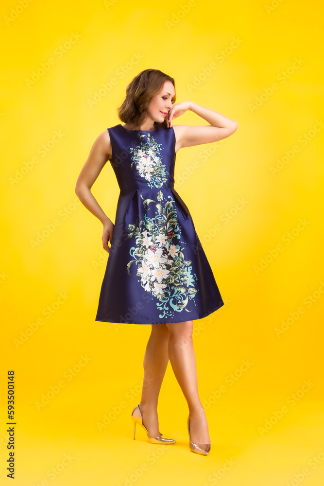 Elegant fashion. Stunning woman in elegant long dress in studio stands on a yellow sunny background. Elegant fashion. Stunning woman in elegant long dress in studio stands on a yellow sunny background.