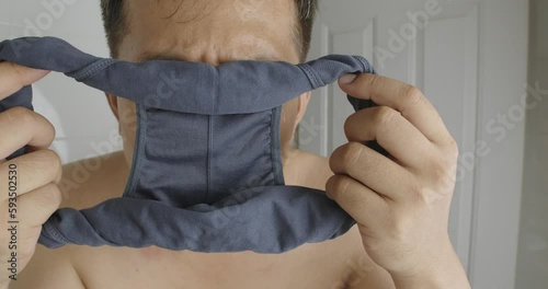 Asian man holding underpants and sniffing smell close-up.