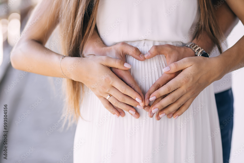 man and woman holding hands in the shape of a heart on a big belly, a ...