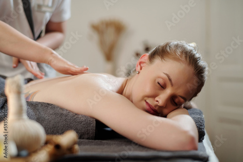 Young woman getting back massage with oils in spa salon
