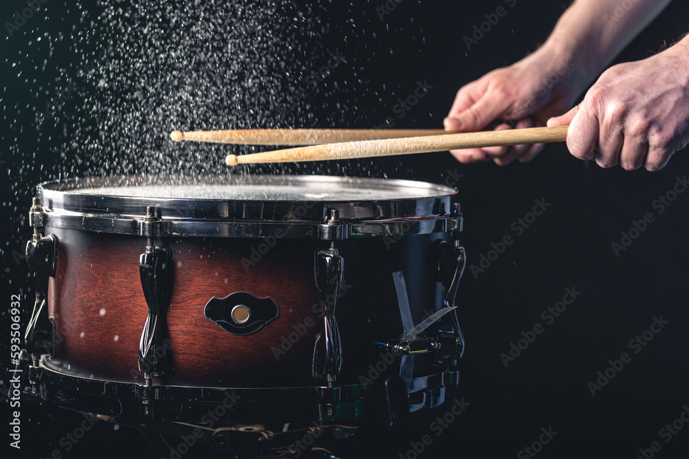 Obraz premium Drummer using drum sticks hitting snare drum with splashing water.