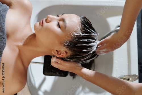 Hairdresser washing hair of client with moisturizing shampoo