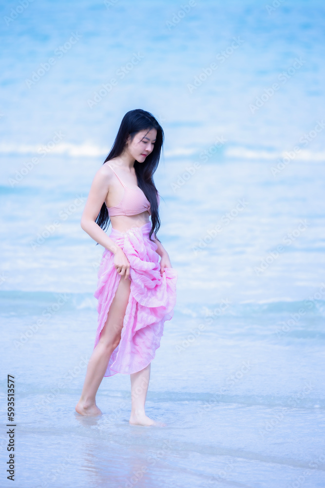 Beautiful woman relax and walking on sandy beach near waving foamy sea. Woman traveler smiling and walks barefoot on the beach. Young woman happy in walks along seashore. Summer vacation concept. Beautiful woman relax and walking on sandy beach near waving foamy sea. Woman traveler smiling and walks barefoot on the beach. Young woman happy in walks along seashore. Summer vacation concept.