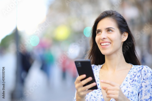 Happy woman holding phone looks up