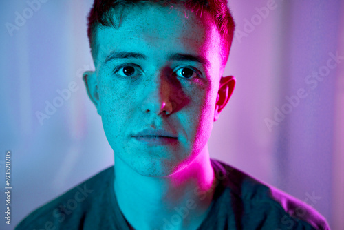 Sad young man with illuminated neon lighting on face photo