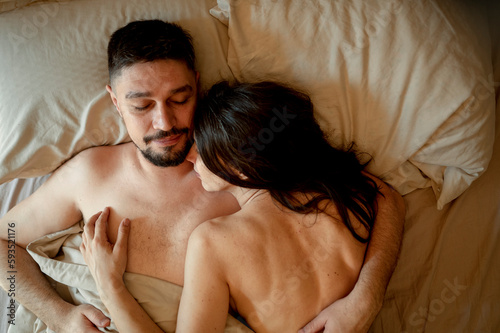 Man embracing woman sleeping on bed at home photo