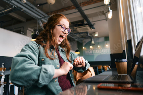 Successful young freelancer screaming at cafe photo