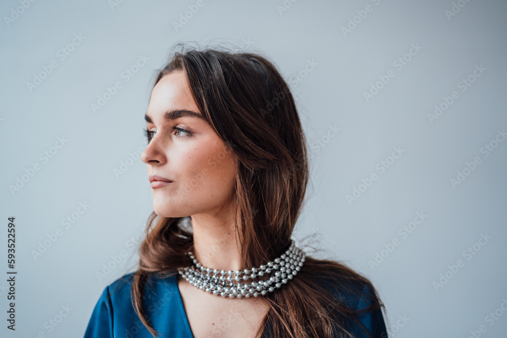 Thoughtful businesswoman wearing silver jewelry in front of wall Thoughtful businesswoman wearing silver jewelry in front of wall