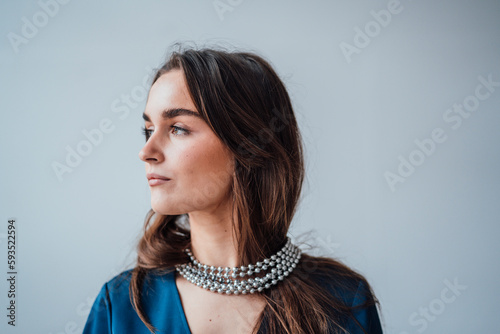 Thoughtful businesswoman wearing silver jewelry in front of wall photo