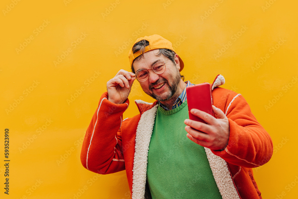 Happy mature man taking selfie against colored background Happy mature man taking selfie against colored background