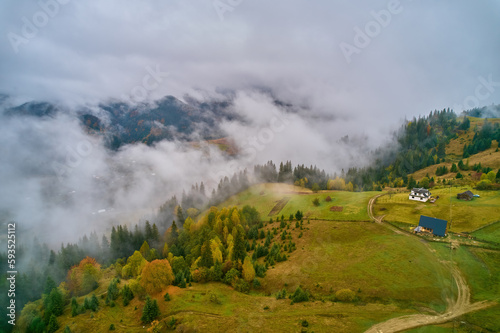 Fog spreads over the mountains at dawn. The sun rises on the horizon. Carpathians in the morning. Aerial drone view.