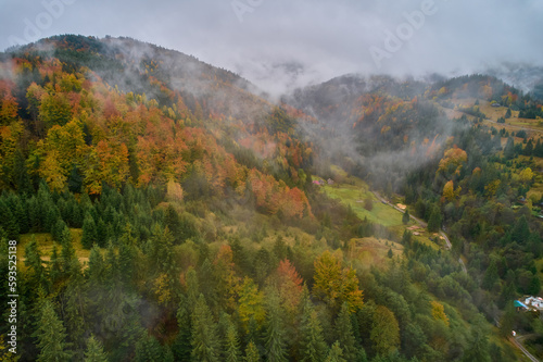 Fototapeta Naklejka Na Ścianę i Meble -  Fog spreads over the mountains at dawn. The sun rises on the horizon. Carpathians in the morning. Aerial drone view.