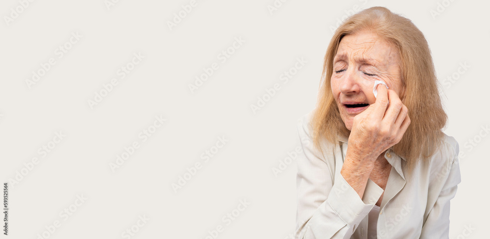 Uneasy distressed old lady feeling sad crying and sobbing wipe tears with tissue Depressed senior woman with depression anxiety depressive illness tired old elderly patient crying isolated on gray Uneasy distressed old lady feeling sad crying and sobbing wipe tears with tissue Depressed senior woman with depression anxiety depressive illness tired old elderly patient crying isolated on gray