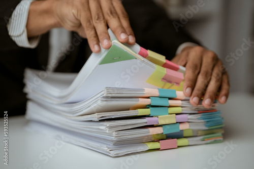 Businesswoman working in stacks of paperwork files for searching infomation unfinished documents about pile audit form on desk office and investigate financial doc in busy workload