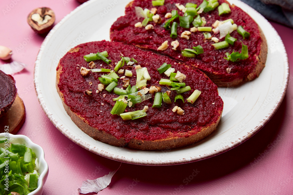 Close up of beetroot spread sandwiches with spring young onion, garlic and walnuts. Vegan healthy snacks food. Top view